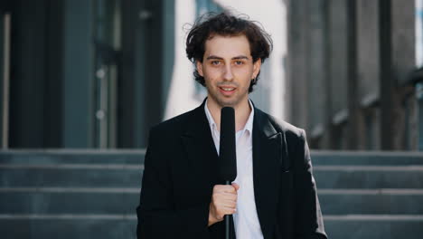 male reporter holding microphone outdoors