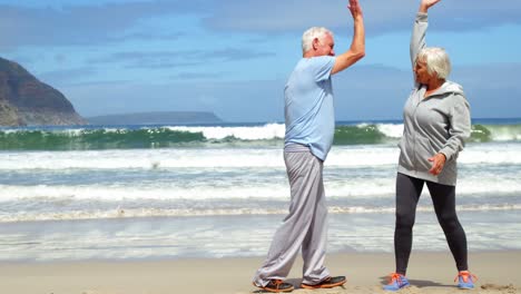 una pareja de alto nivel dando cinco en la playa.