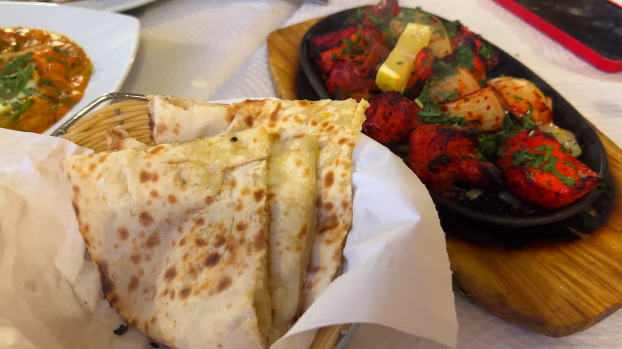 People enjoying traditional Indian dishes with cheese naan bread and coconut rice in a restaurant, authentic Asian food, 4K shot