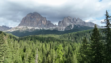 dolomites alpine woodland push in slowly flying across treetops towards epic italian mountain range