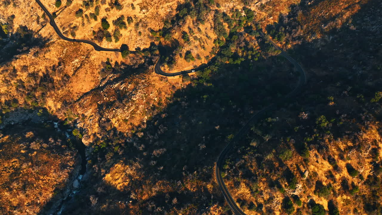 Mountainous landscape crossed by the wavy road. California rocky panorama from top at sunset.