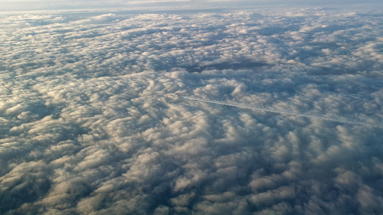 vista increíble desde la cabina de un avión que vuela alto por encima de las nubes dejando un largo rastro de aire de vapor de condensación blanco en el cielo azul