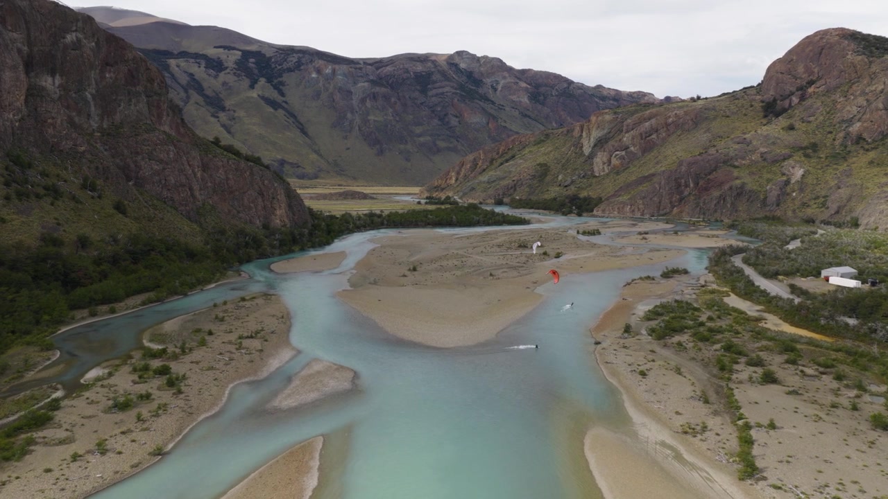 Paragliders soar above braided glacial channels near El Chaltén, Santa Cruz, Patagonia Argentina, adventure tourism and free flight sports over turquoise meltwater, alluvial bars, drone tracking