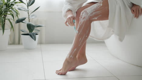 woman shaving her legs in a bathroom