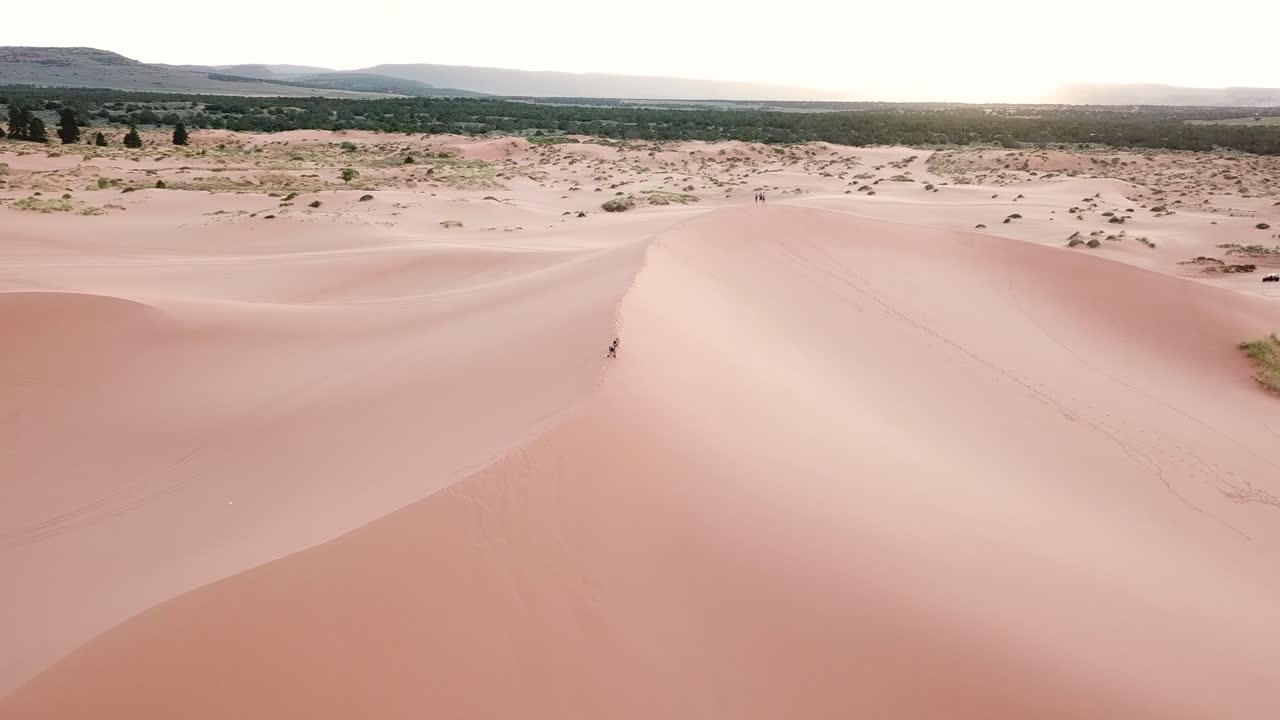 vista aérea de personas caminando en una colina arenosa en el parque estatal de dunas de arena rosa de coran, utah, ee.uu.