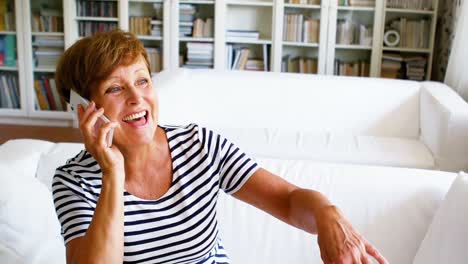 Mujer-Mayor-Hablando-Por-Teléfono-Móvil-En-La-Sala-De-Estar