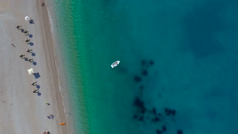 Paradise-beach-with-umbrellas-and-sunbeds-on-sand-washed-by-clear-turquoise-sea-water-in-Ionian-coastline