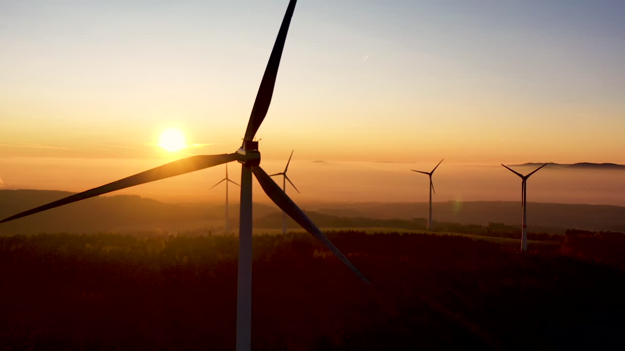 Aerial View of Wind Turbines Silhouettes With Blades Spinning in Front of Sunset , Alternative Sustainable Power and Energy Concept, Cinematic Drone Shot