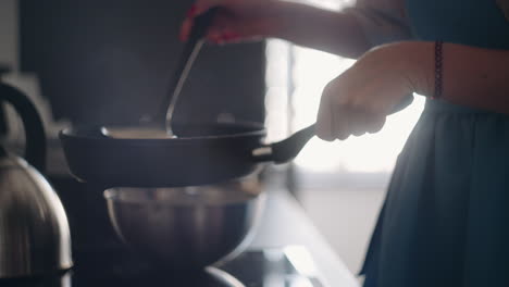 La-Señora-Está-Cocinando-El-Desayuno-Friendo-Panqueques-Vertiendo-Masa-En-Una-Sartén,-Vista-De-Cerca,-Mañana-Tranquila-Entre-Semana.