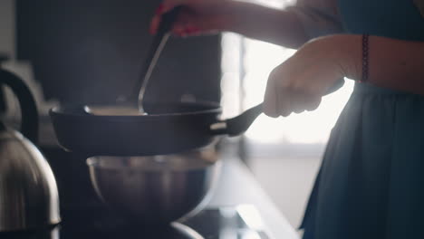 lady is cooking breakfast frying pancakes pouring dough on frying pan closeup view calm weeked morning