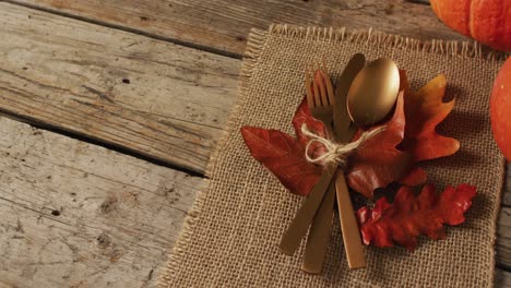 video of cutlery, cloth and autumn decoration lying on wooden surface