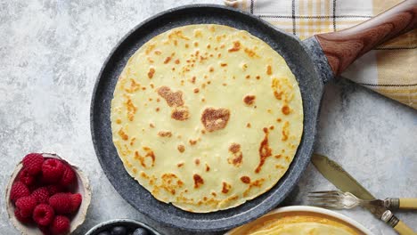 deliciosos panqueques en sartén de piedra colocados en la mesa con varios ingredientes