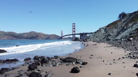 Aufsteigende-Aufnahme-Der-Golden-Gate-Bridge-Am-Baker-Beach-Mit-Brechenden-Wellen