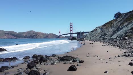 rising shot of golden gate bridge at baker beach with waves crashing