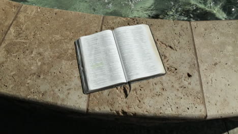 holy book by a peaceful water fountain background in slow motion