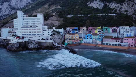 Luftaufnahme-Von-Wellen,-Die-An-Der-Katalanischen-Bucht-Mit-Bunten-Gebäuden-Am-Strand-Brechen