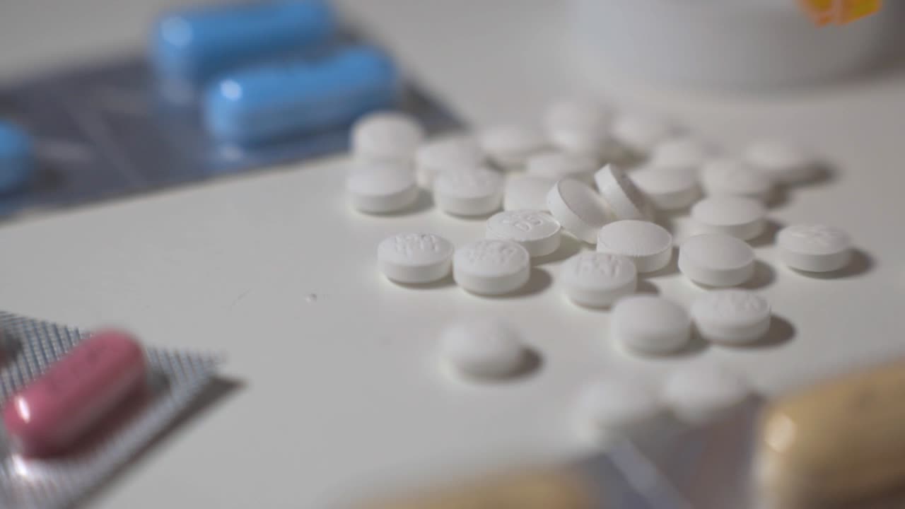 Dropping White Pills And Tablets Scattered On A White Table - Closeup Shot