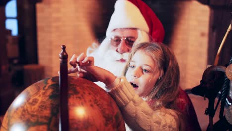 little girl points a finger to santa claus on a retro globe lapland and the north pole