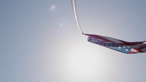 American-flag-waving-on-a-pole-against-the-blue-sky-and-sun