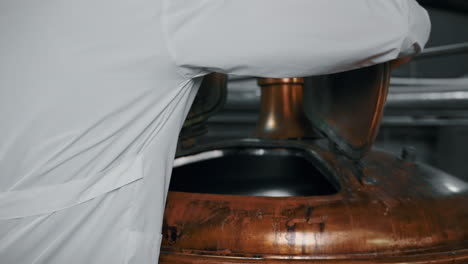 brewery worker opening a copper brew tank