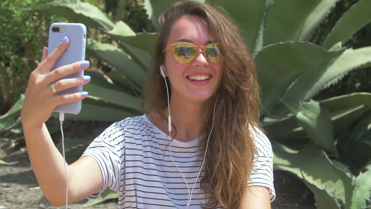 mujer tomando una selfie con su teléfono mientras sonríe