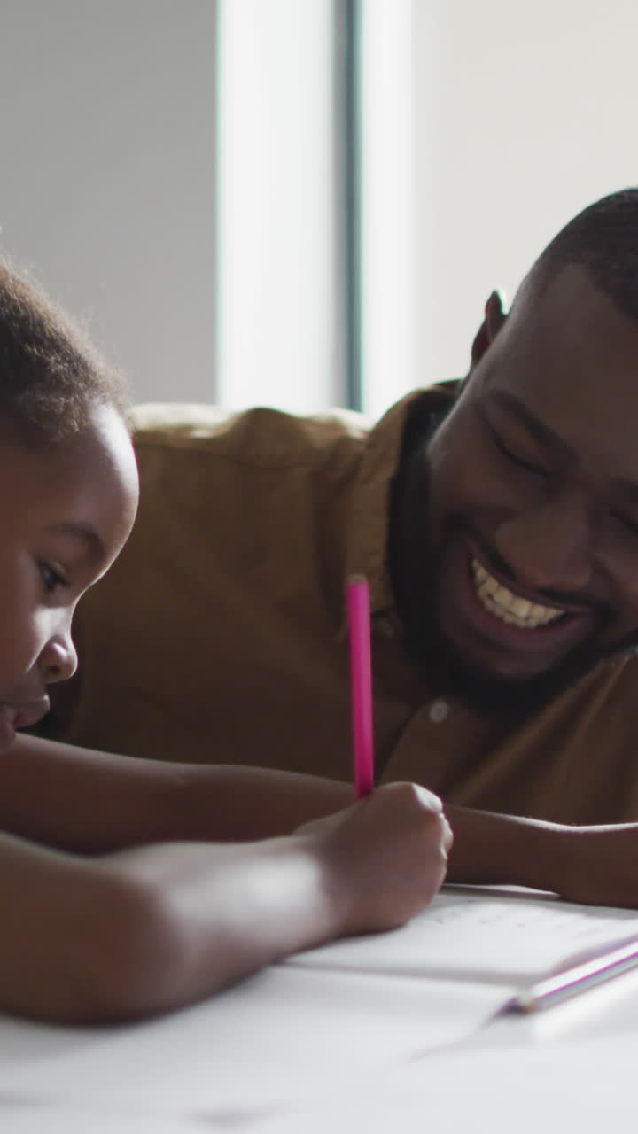 Video of happy african american male teacher helping in lessons to african american girl