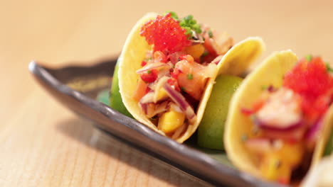 delicious tacos in a plate filled with mixed onions and tomatoes topped with caviar - close up