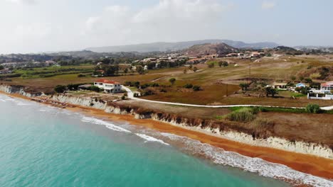 panoramic view of turquoise sea and red sand shore of megas lakkos beach in greece - aerial drone shot