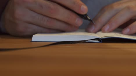 man opening notebook then writing in it