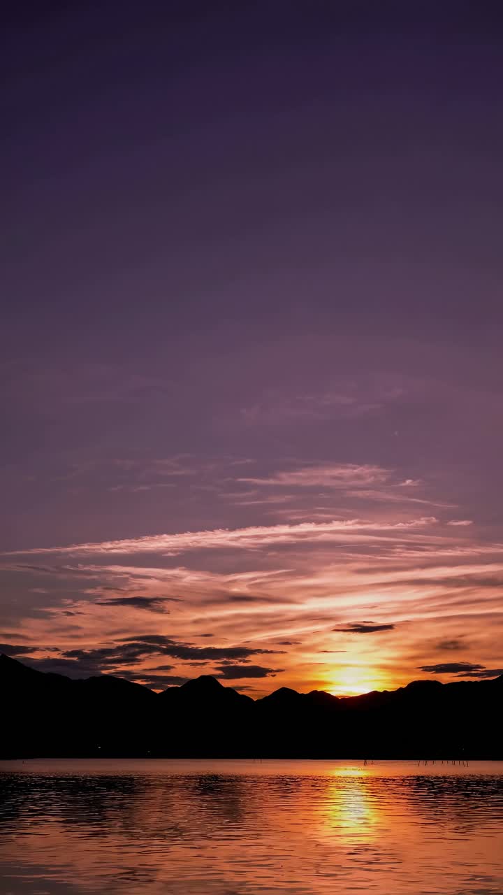 A serene sunset over mountains and a lake, captured from a low angle