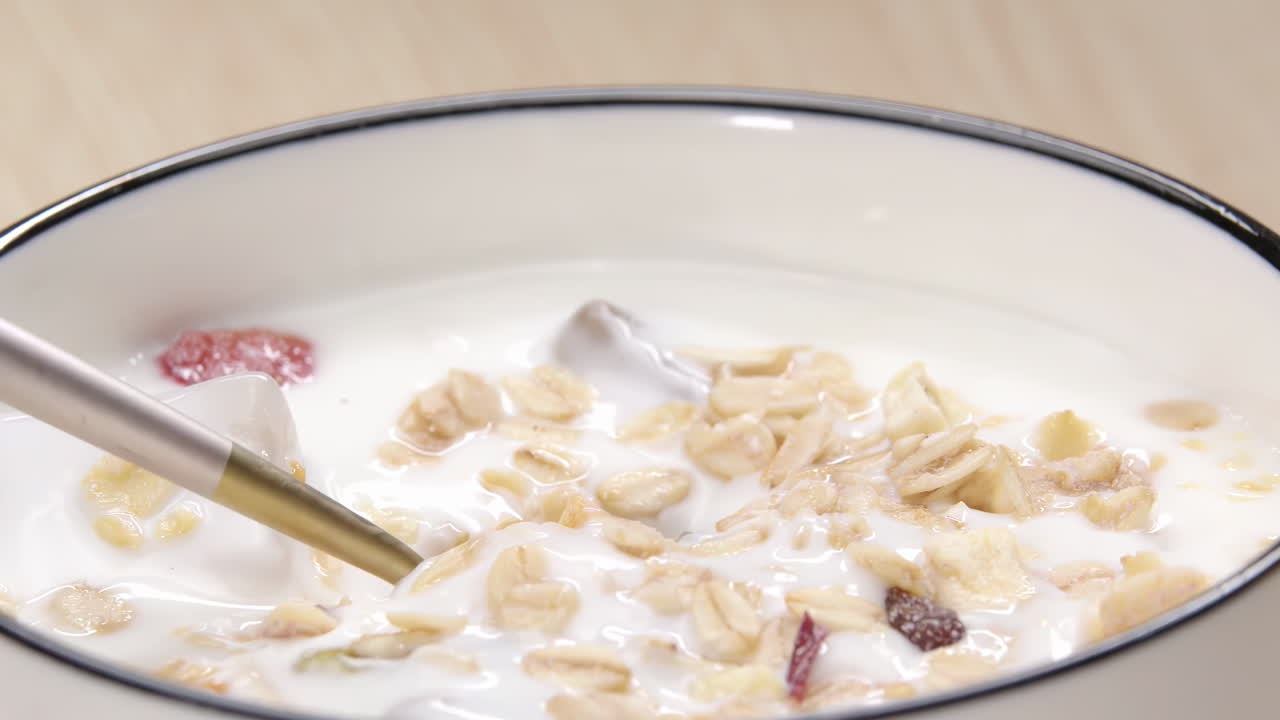 Una scena di colazione rinfrescante, salutare e nutriente, ispirata a uno stile di vita sano, con un cucchiaio che preleva yogurt, granola e frutta da una ciotola. Cibo naturale per energia e benessere. Delizioso spuntino dolce