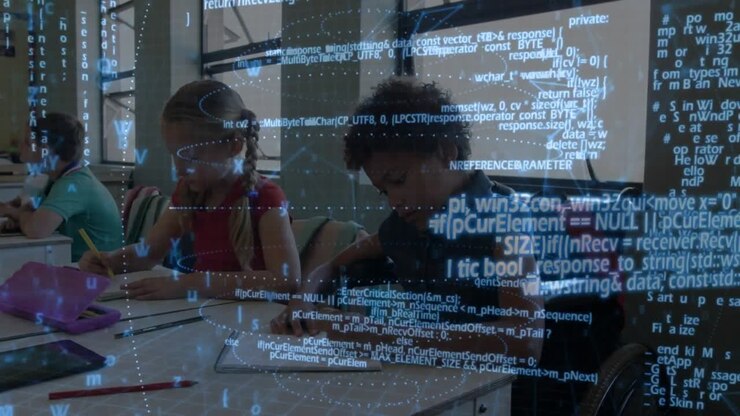 Wheelchair pupil writing with peers on notes and classwork while projecting code overlay over table