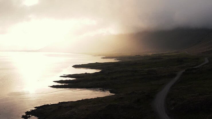 Silhouette of coastal environment in Iceland with bright sunshine between clouds