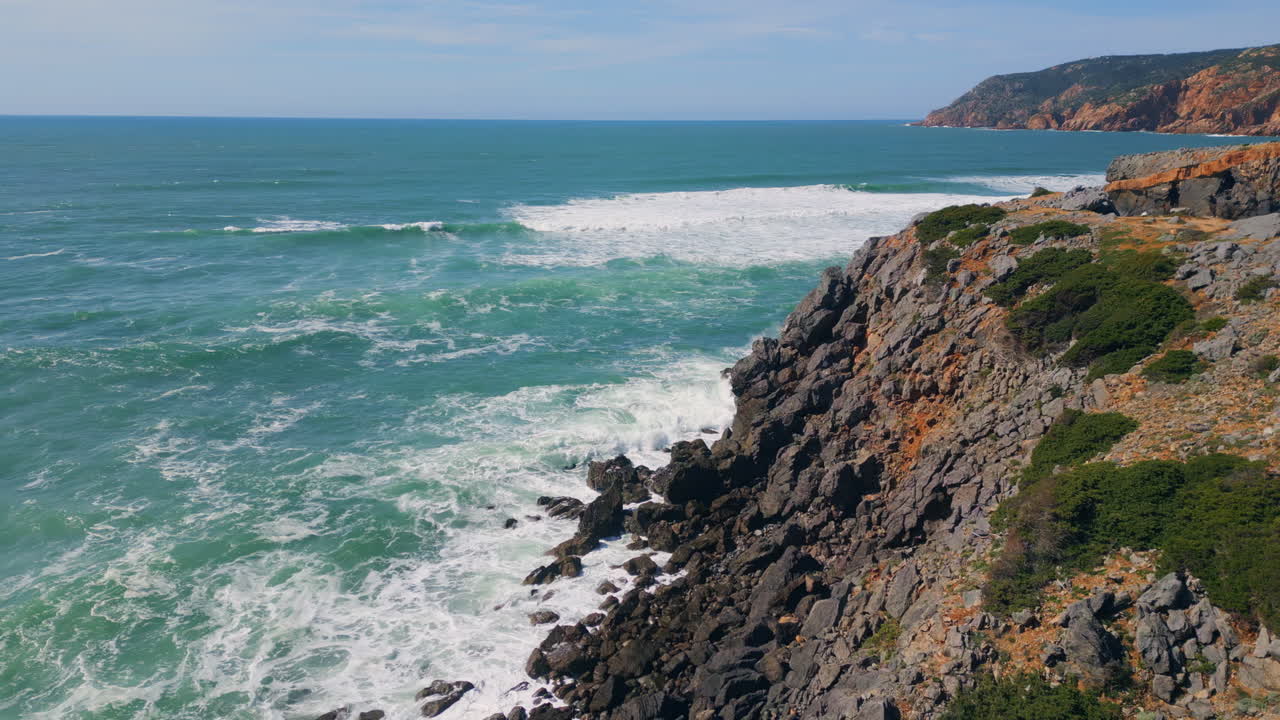 Powerful ocean meeting rocky coast splashing. Rough sea water foaming drone view