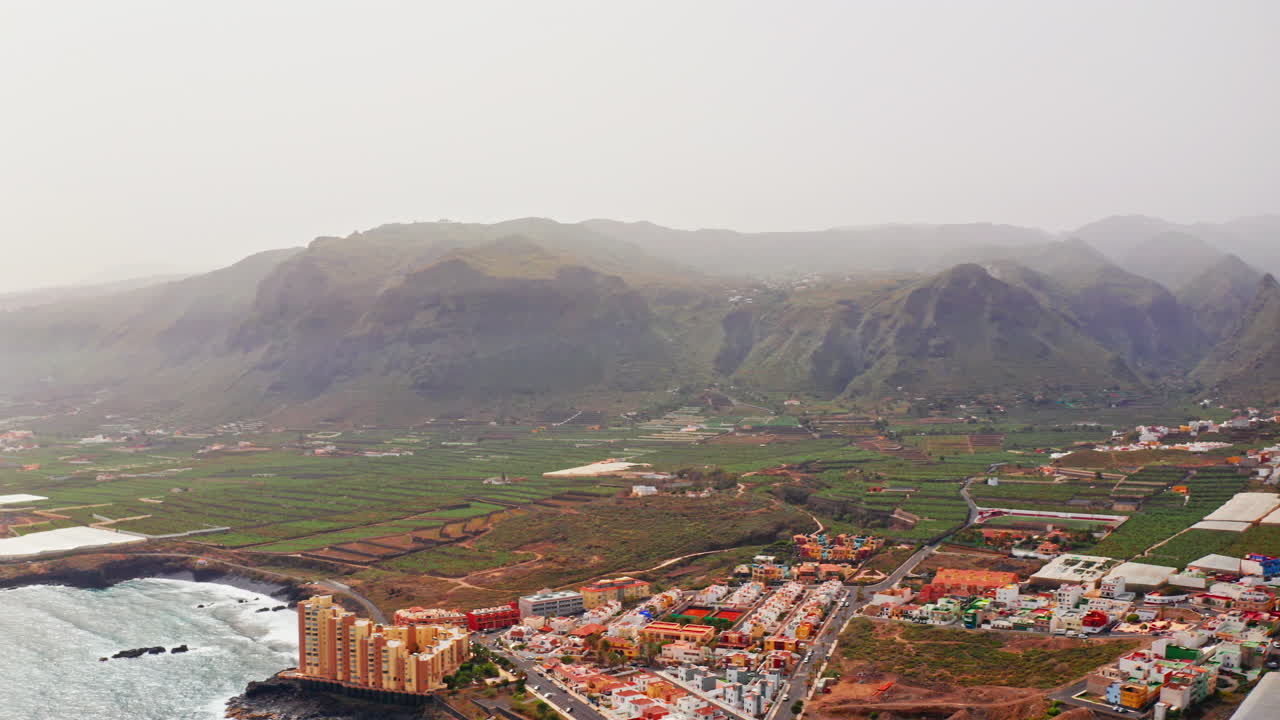 drone aéreo disparado sobre la costa de tenerife, islas canarias, españa. alta vista del mar, costa volcánica rocosa y las montañas en la distancia.