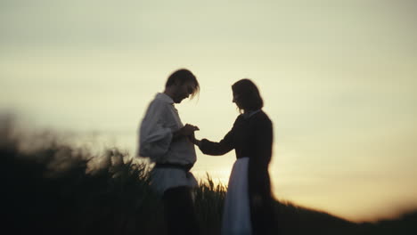 silhouetted couple in a field at sunset