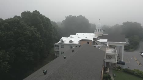 foggy aerial flies low over roof top of lambuth inn on lake junaluska