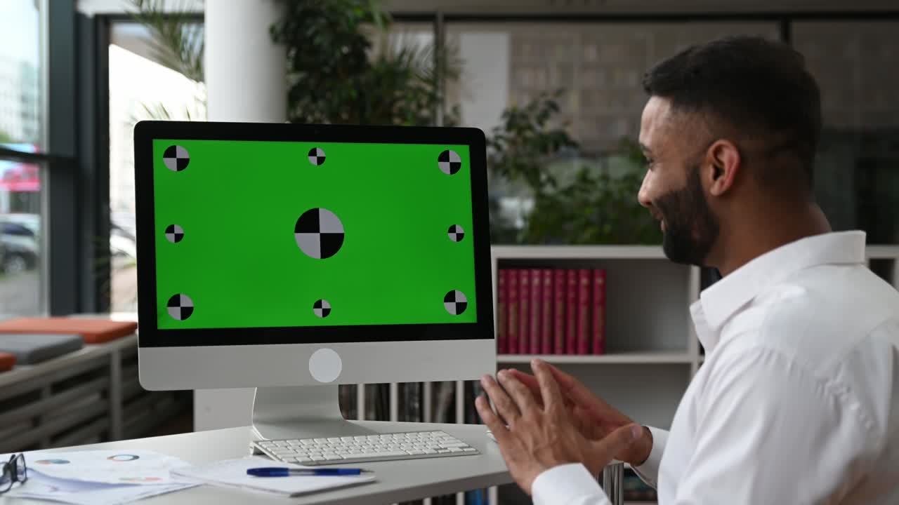el concepto de pantalla verde en blanco de la computadora. hombre de negocios indio, se sienta en el lugar de trabajo, se comunica por llamada de video con los socios, discute una estrategia, muestra un gráfico financiero, habla de problemas de trabajo