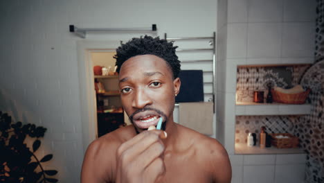 young black man brushing his teeth in bathroom during morning routine