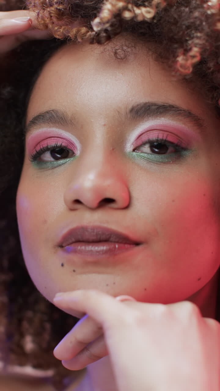 Vertikal video af kvinde af blandet etnicitet med mørkt hår i blåt og pink lys, slowmotion.