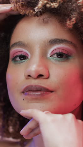 vertical video of biracial woman with dark hair in blue and pink light, slow motion