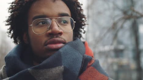 close-up of a man wearing glasses and a scarf in winter