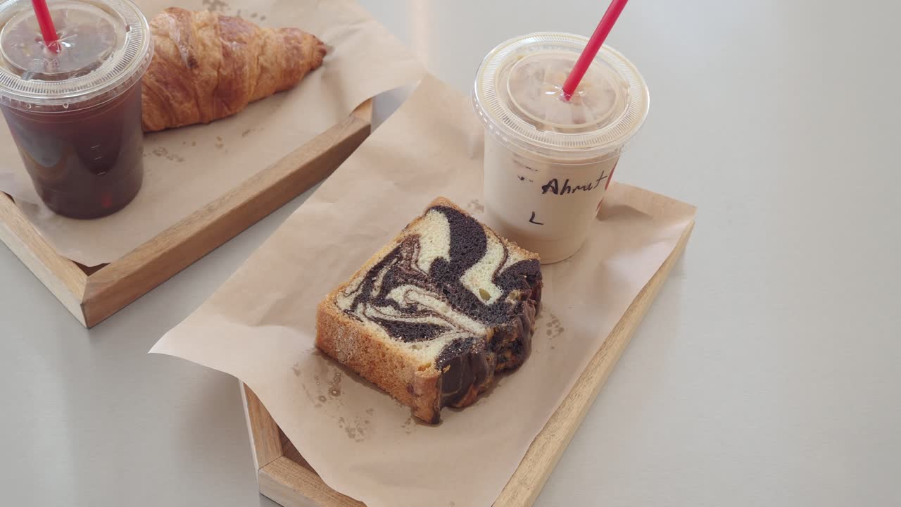 Breakfast or dessert items with iced coffees and a croissant and marble cake on trays