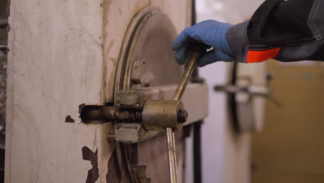 worker with gloved hand operating kiln door lever in a pottery workshop, showcasing craftsmanship and manual labor