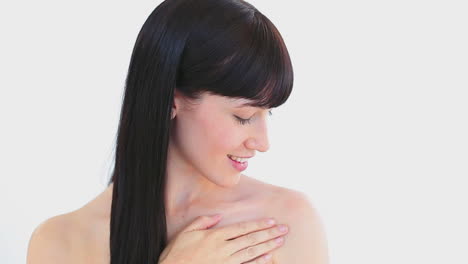 una mujer morena sonriente masajeando su hombro.