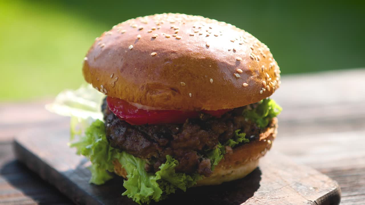 sabrosa hamburguesa de ternera con lechuga, cebolla y tomates servida en el jardín al aire libre