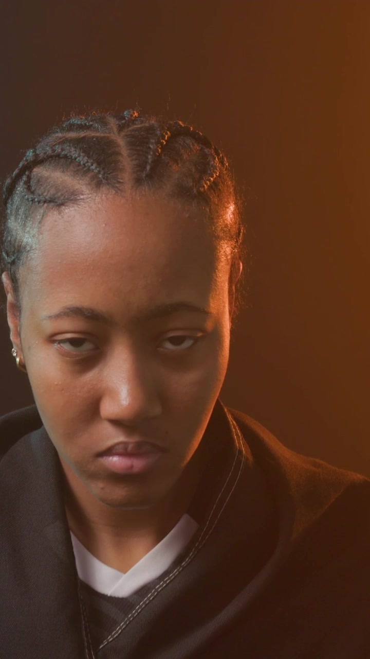 Camera starting tight, woman slowly raising head, revealing braids and red drape, conveying calm