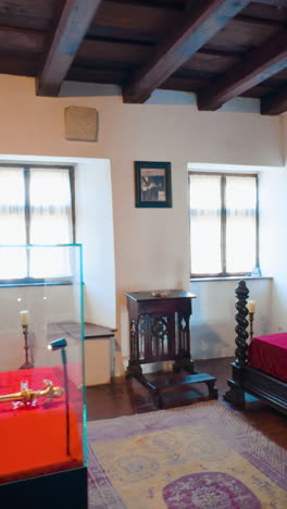 Cozy room with big wooden bed, fireplace and golden crown display. Bedroom interior in Bran castle, Romania. Vertical video
