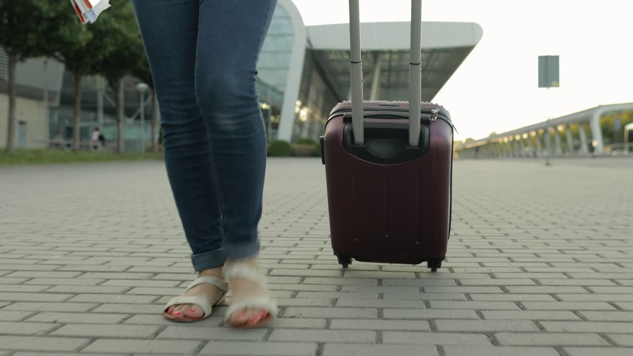 piernas de mujer de negocios turista caminando con equipaje. caminar por la calle con bolsa de maleta en ruedas