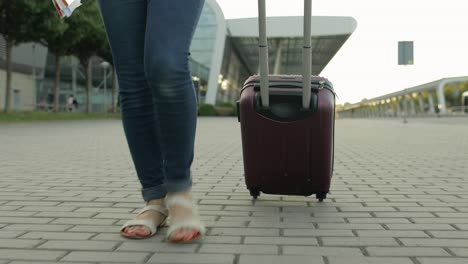 legs of businesswoman tourist walking with luggage. walk down the street with suitcase bag on wheels